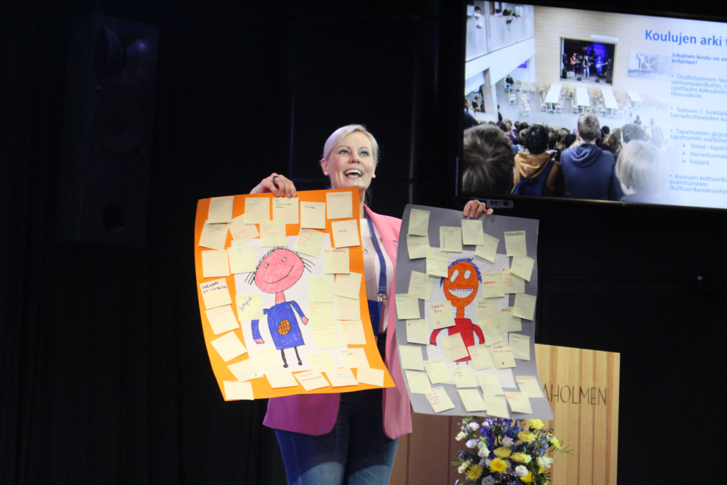 Hankekoordinaattori Tiina Hakio esittelee postereilla oppilaiden harrastustoiveita.